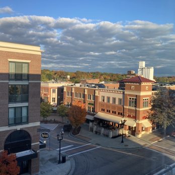 Nineteen10 - a view of a city from a window - A city scene showing multi-story buildings, trees with fall foliage, and a partly cloudy sky, taken from an elevated perspective. - Cocktail Bars Near Me - Kent, Ohio