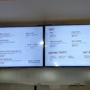 Ghost Chicken - A digital menu board shows various food items including sandwiches, fried chicken, sides, and soft drinks, with a cartoon chicken drawing on the right. - Comfort Food Near Me - Toronto, Ontario