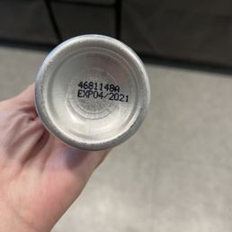 a person's hand holding a can