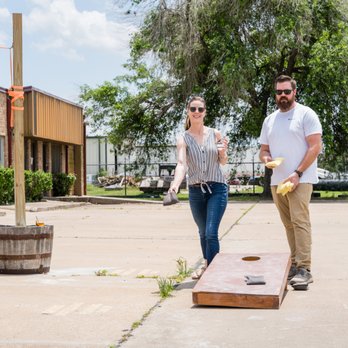 Shire Distilling - a man and a woman playing corn hole - Whiskey Bars Near Me - Houston, Texas Shire Distilling - a man and a woman playing corn hole - Whiskey Bars Near Me - Houston, Texas