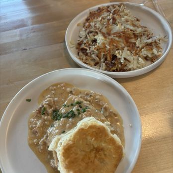 Twisted Egg - Biscuits and gravy with hash browns with bowl of yogurt and berries in the background - Breakfast & Brunch Near Me - Aurora, Colorado