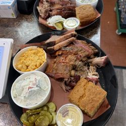 Three meat platter with brisket, ribs, pulled pork, and cornbread. Sides: Mac & cheese, fresh cucumber salad, pickles, and cowboy beans