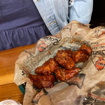 Roosters - a person sitting at a table with a bag of chicken wings - American Near Me - Louisville, Kentucky Roosters - a person sitting at a table with a bag of chicken wings - American Near Me - Louisville, Kentucky