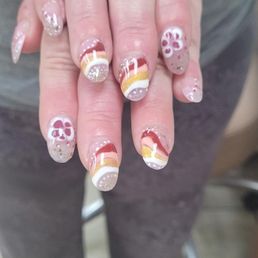 What a great place. Love Amy. She makes u feel like family - Hands with manicured nails displaying floral and striped nail art designs, including glitter accents.