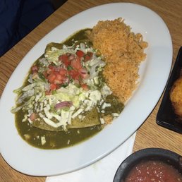 Crab Enchiladas - A Mexican dish served with rice, a salad topping, and a main item covered in green sauce on a white plate.