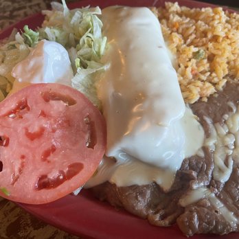 El Rodeo - Beef Chimichanga! - A Mexican dish plate includes rice, refried beans with cheese, shredded lettuce, a slice of tomato, and a beef chimichanga topped with sour cream. - Mexican Near Me - Clive, Iowa