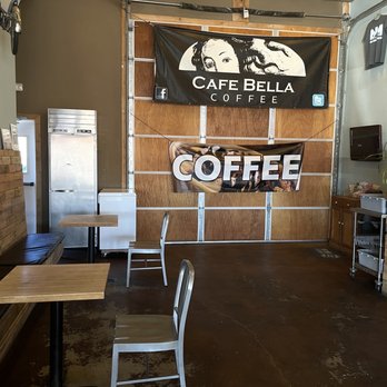 Cafe Bella Coffee - The only 2 tables across from the coffee station. - Inside Cafe Bella Coffee, there are wooden tables, metal chairs, and banners on the wall advertising coffee. The space has a simple, modern decor. - Coffee & Tea Near Me - Rio Rancho, New Mexico