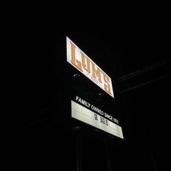 Lum's - Outside - A nighttime photograph features an illuminated sign for Lum's restaurant, with the main sign displaying the name 'LUM'S' in large, bold letters. Below, a message board shows the text 'FAMILY OWNED SINCE 1976' and 'GO EAGLES!'. The background is dark, with no other visible structures or details, emphasizing the lit signage. - Barbeque Near Me - Junction, Texas