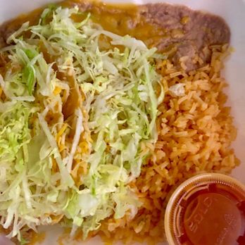 Los Cerritos - Chicken tacos combo with rice and beans. Delicious comfort food! - A takeout meal in a foam container includes shredded lettuce on top of tacos, Mexican-style rice, refried beans, and a small plastic cup of salsa. The lettuce appears fresh, and the rice and beans are cooked, with the salsa in a clear plastic cup. The meal is typical of Mexican cuisine, served for quick pickup or delivery. - Mexican Near Me - Phoenix, Arizona