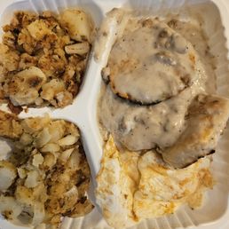 Biscuits and gravy, home fries, and two over easy eggs for $8.79! - A compartmentalized tray contains biscuits with gravy, seasoned home fries, and scrambled eggs, typical of breakfast offerings.