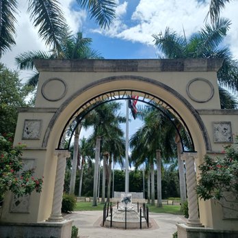 Memorial Park - An archway with decorative columns marks the entrance to a memorial park, with palm trees and a flag visible behind it. - Parks Near Me - Stuart, Florida