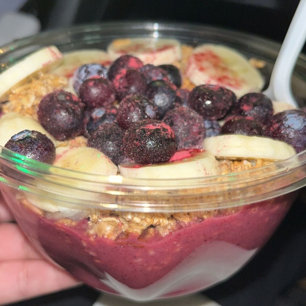 a hand holding a bowl of fruit