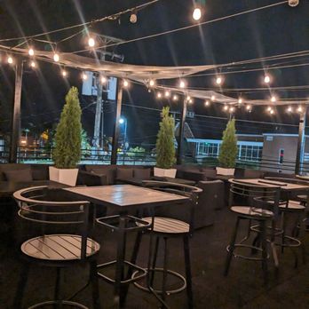 120 West - tables and stools under string lights - Wine Bars Near Me - Brighton, Michigan
