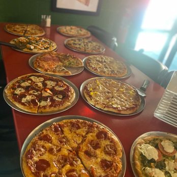 Tipsy Tomato - a long table with pizzas on it - Pizza Near Me - Cedar Rapids, Iowa