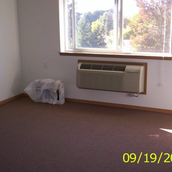 Foothill Retirement Centers I & II - Living room view of the assigned parking spot, garden area, and hills. A/c and heat unit under window, mini blinds and glue down carpeting. - Apartments Near Me - Grants Pass, Oregon Foothill Retirement Centers I & II - Living room view of the assigned parking spot, garden area, and hills. A/c and heat unit under window, mini blinds and glue down carpeting. - Apartments Near Me - Grants Pass, Oregon