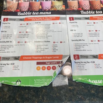 J M Global - Two bubble tea menus displaying options for tea types, flavors, toppings, and sugar levels, placed on a dark countertop surface. - Coffee & Tea Near Me - Chantilly, Virginia