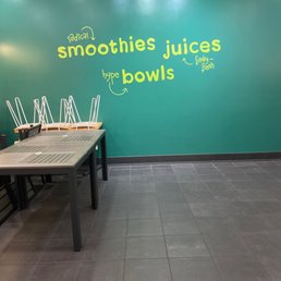 a table and chairs in front of a wall that says smoothies juices a table and chairs in front of a wall that says smoothies juices