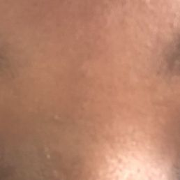 A detailed close-up of a person's face showing closed eyes and well-groomed eyebrows. The skin appears smooth, and the eyebrows are neatly shaped, possibly indicating a recent eyebrow threading or grooming service. The image emphasizes the eye area and eyebrow shape.