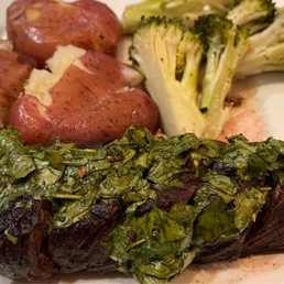 Hanger Steak - A dish featuring hanger steak with chimichurri sauce, roasted potatoes, and steamed broccoli on a white plate.