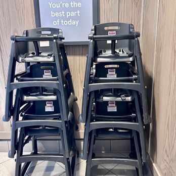 Chick-fil-A - Highchairs - Two stacks of black high chairs are positioned against a wooden wall, with a sign above that reads 'You're the best part of today.' - Fast Food Near Me - Paramus, New Jersey
