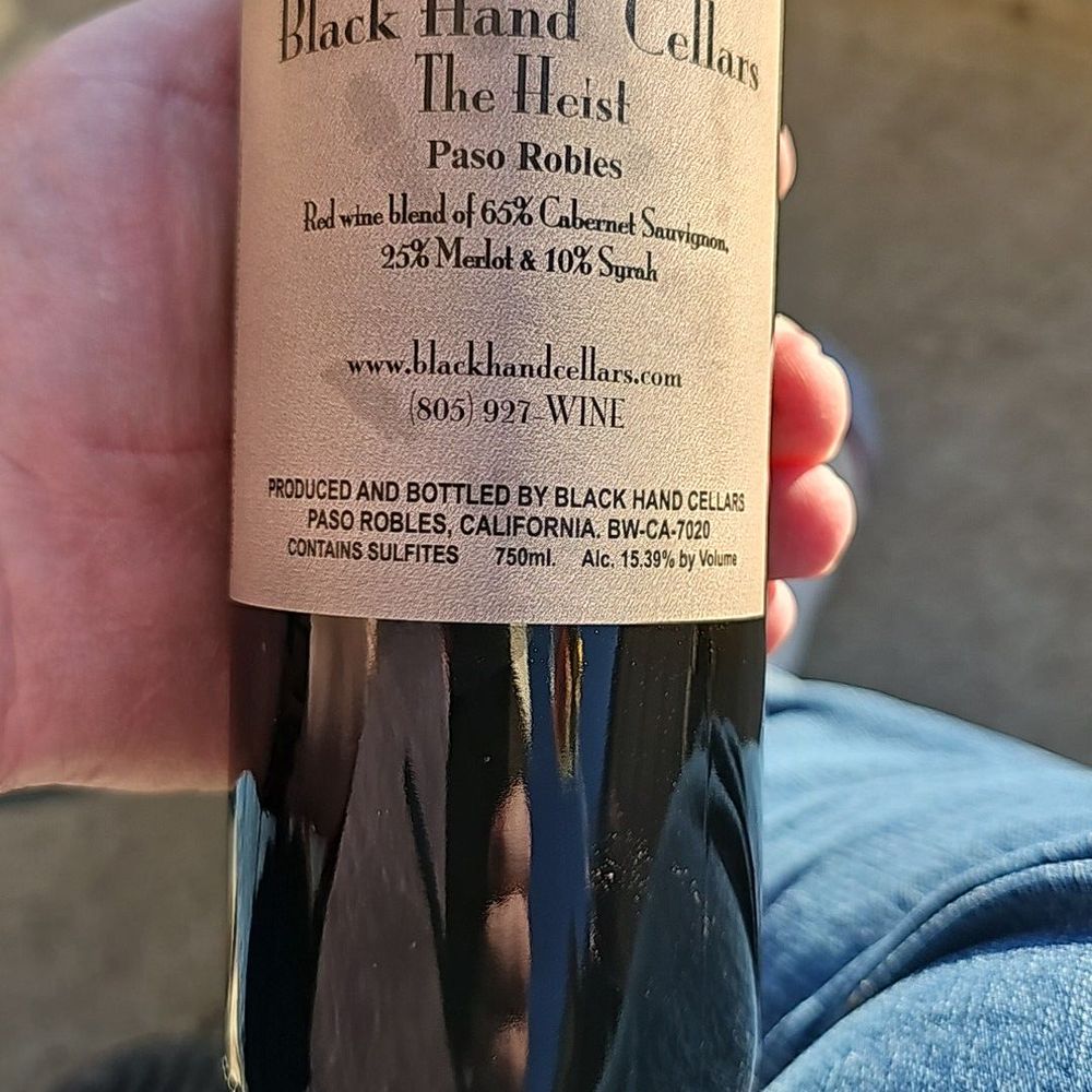 a hand holding a bottle of wine