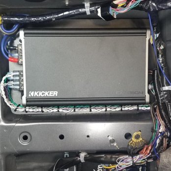 North County Mobile Electronics - Amplifier and wiring - A Kicker car audio amplifier is mounted inside a vehicle, with various wires and cables connected for electronic upgrades. - Car Stereo Installation Near Me - Oceanside, California