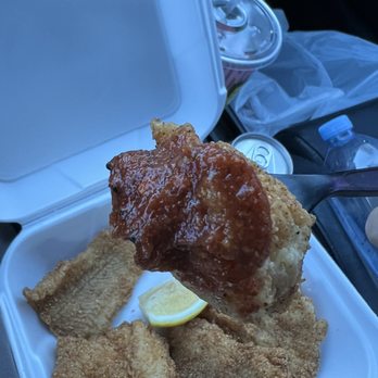 Bayou Grille - a hand holding a piece of fried chicken - Cajun/Creole Near Me - Inglewood, California