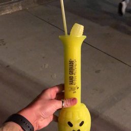 a hand holding a yellow plastic cup with a straw sticking out of it a hand holding a yellow plastic cup with a straw sticking out of it