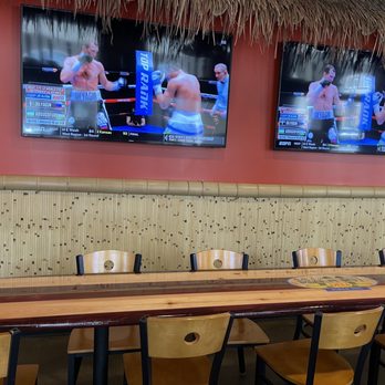 Beach Hut Deli - a row of wooden tables and chairs in front of televisions - Delis Near Me - Oceanside, California Beach Hut Deli - a row of wooden tables and chairs in front of televisions - Delis Near Me - Oceanside, California
