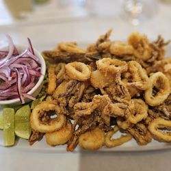 Mistura Peruana - Chicharrón de calamar (crispy fried calamari), a popular Peruvian seafood dish served with red onion salsa (salsa criolla) and lime wedges.