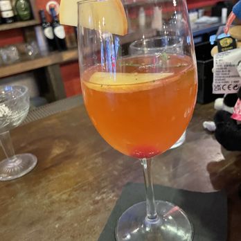 Silver Strings - Drink - A drink in a wine glass garnished with an apple slice, set on a bar counter with a background of bottles and barware. - Bars Near Me - Silver Spring, Maryland