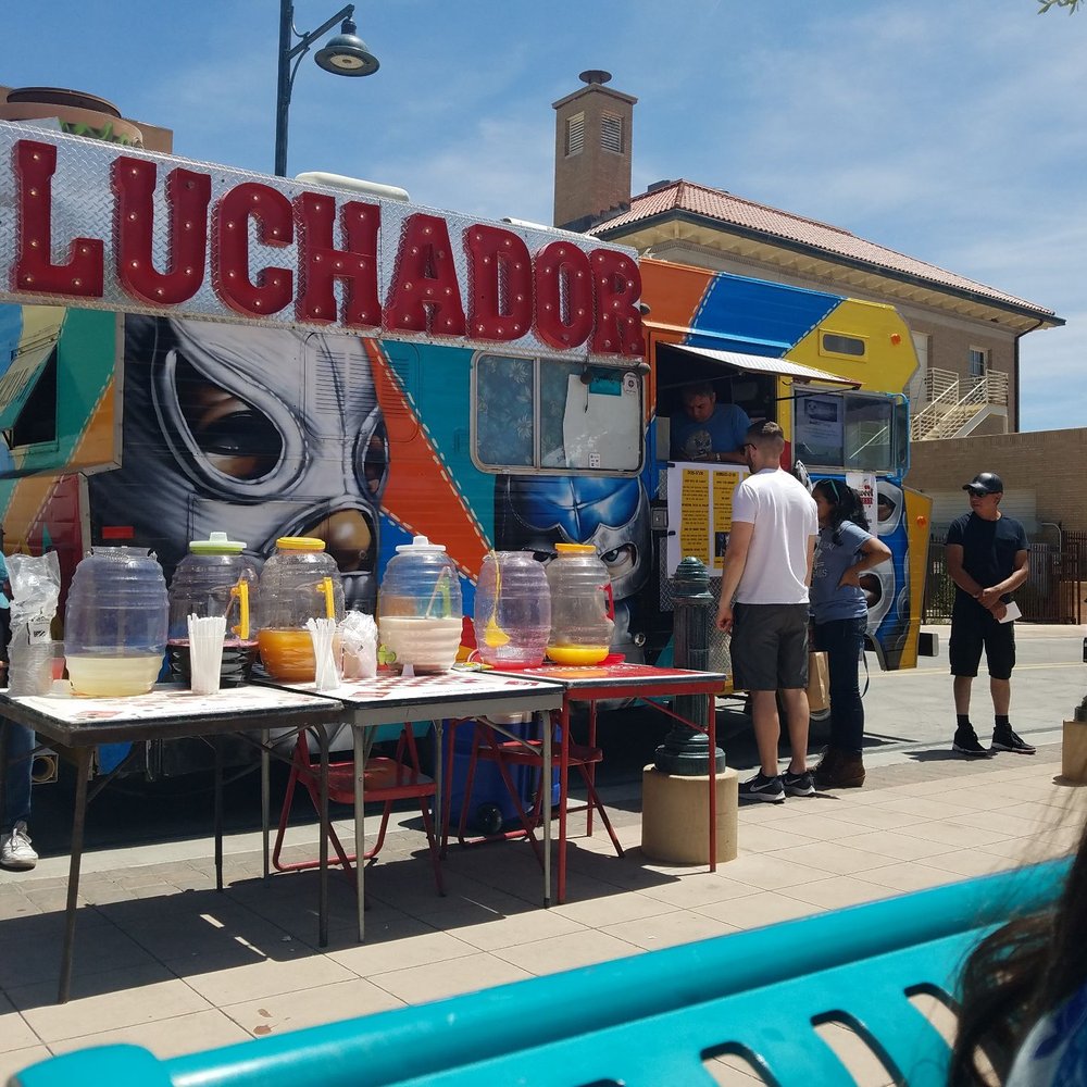 people standing in front of a food stand people standing in front of a food stand