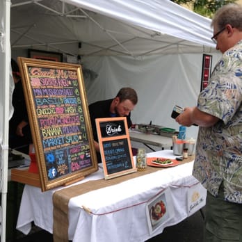 Gnocchi Me - a man standing in front of a table with a menu on it - Street Vendors Near Me