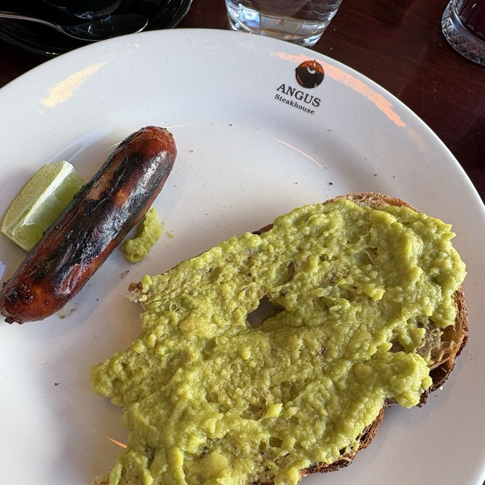Angus Steakhouse - The avocado toast, after she took a couple bites, note the hole that the spread fell through onto her clothes. And that sausage. - Steakhouses Near Me - London, XGL Angus Steakhouse - The avocado toast, after she took a couple bites, note the hole that the spread fell through onto her clothes. And that sausage. - Steakhouses Near Me - London, XGL
