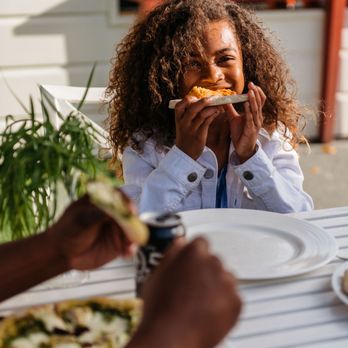 Forno Pizza - a woman eating a slice of pizza - Pizza Near Me - Napa, California