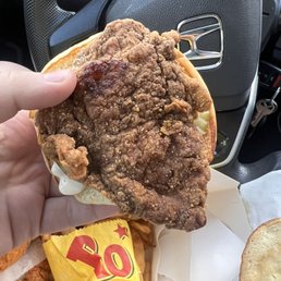 a hand holding a fried chicken sandwich