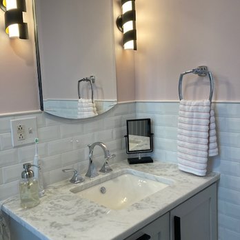 DJ Marble & Granite - A bathroom vanity with a marble countertop, a mirror, wall-mounted light fixtures, and a towel ring with a towel. - Countertop Installation Near Me - Addison, Illinois