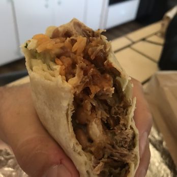 Tacos Correa - a hand holding a burrito - Mexican Near Me