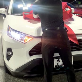 Priority Toyota Springfield - Gideon (Sales & Leasing Consultant) placing a fancy red bow on my brand new car The best!! - Car Dealers Near Me - Springfield, Virginia
