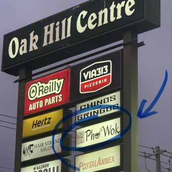 Pho Wok - A tall business sign for Oak Hill Centre displays multiple store signs, including Pho Wok, a Vietnamese restaurant, with a blue circle and arrow pointing to it. - Vietnamese Near Me - Austin, Texas