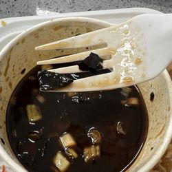 Ed Youngs Chinese Restaurant - Orange chicken sauce but do you see all the burnt bits. It's even on the container. The container is LITERALLY black.