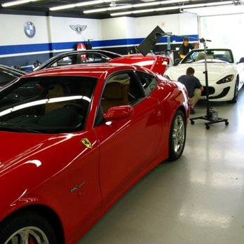 Dent Kraft PDR - A red Ferrari 612 Scaglietti is parked in a detailing shop with other luxury cars, including a white Maserati, undergoing wor... - Mobile Dent Repair Near Me - Eden Prairie, Minnesota Dent Kraft PDR - A red Ferrari 612 Scaglietti is parked in a detailing shop with other luxury cars, including a white Maserati, undergoing wor... - Mobile Dent Repair Near Me - Eden Prairie, Minnesota
