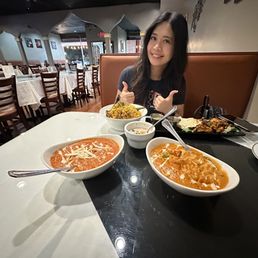 a woman sitting at a table with bowls of food a woman sitting at a table with bowls of food