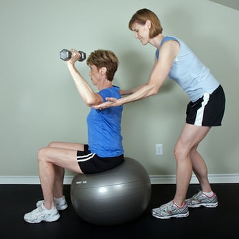 Inspired Training - Kimberly assists client with military press. - Trainers Near Me Inspired Training - Kimberly assists client with military press. - Trainers Near Me