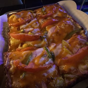 Molten Monkey - Pizza - A rectangular pizza with melted cheese, tomato slices, green peppers, and other vegetables, served on a tray with parchment paper. - Pizza Near Me - Madison, Wisconsin