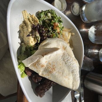 Pinched on the River - beef chevaps with couscous, taboli, sautéed onions, hummus, greens, and pita - Mediterranean Near Me - Chicago, Illinois Pinched on the River - beef chevaps with couscous, taboli, sautéed onions, hummus, greens, and pita - Mediterranean Near Me - Chicago, Illinois