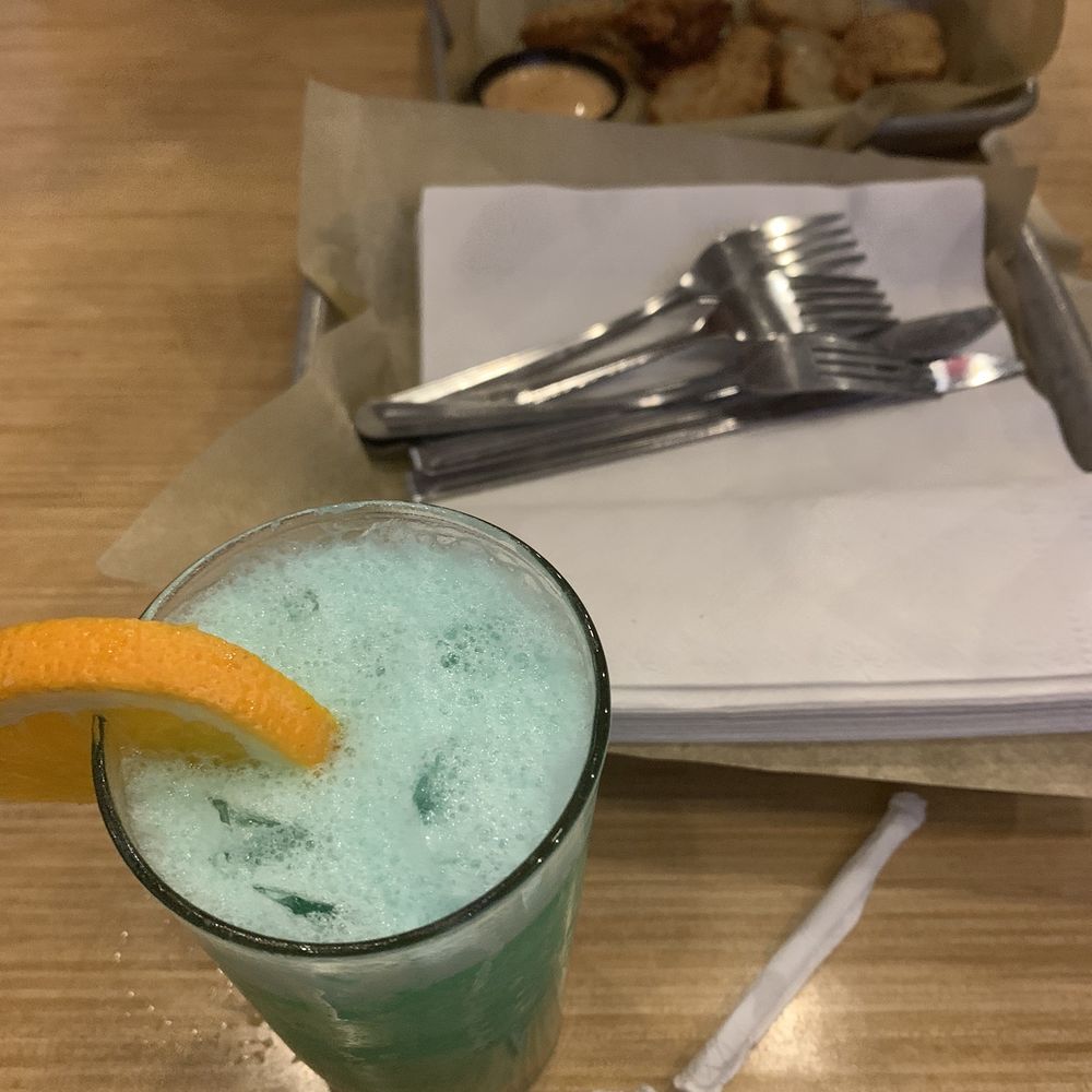 a glass of green drink with a slice of orange a glass of green drink with a slice of orange
