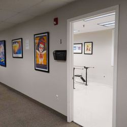 Binson's Medical Equipment & Supplies - An open doorway in a medical office hallway, showing a patient consultation room with parallel bars for physical therapy or o...
