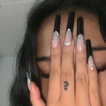 Nail Tech - this is the inspiration photo i used from pinterest - A woman with long, decorated nails covers her face with her hand, revealing a small tattoo on her finger and earrings. - Nail Salons Near Me - Oroville, California