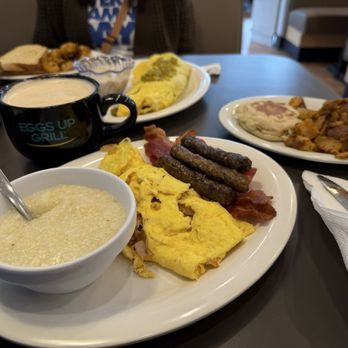 Eggs Up Grill - Cafe Latte, scrambled eggs with sautéed onions, sausage links, bacon, grits, an English muffin and home fries. - Breakfast & Brunch Near Me - Greenville, North Carolina Eggs Up Grill - Cafe Latte, scrambled eggs with sautéed onions, sausage links, bacon, grits, an English muffin and home fries. - Breakfast & Brunch Near Me - Greenville, North Carolina